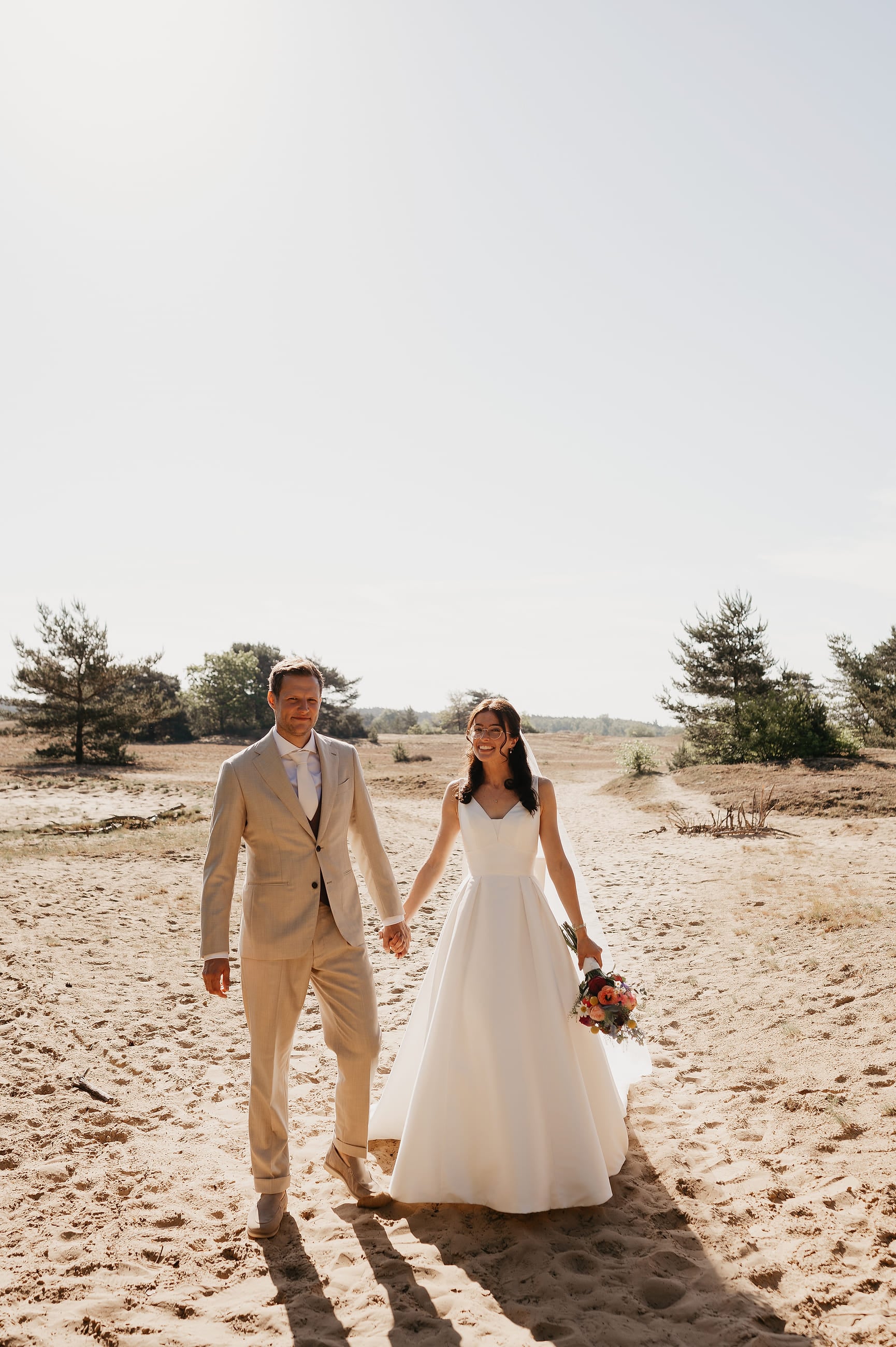 Bruidspaar loopt hand in hand over de heide – Studio Roos Fotografie