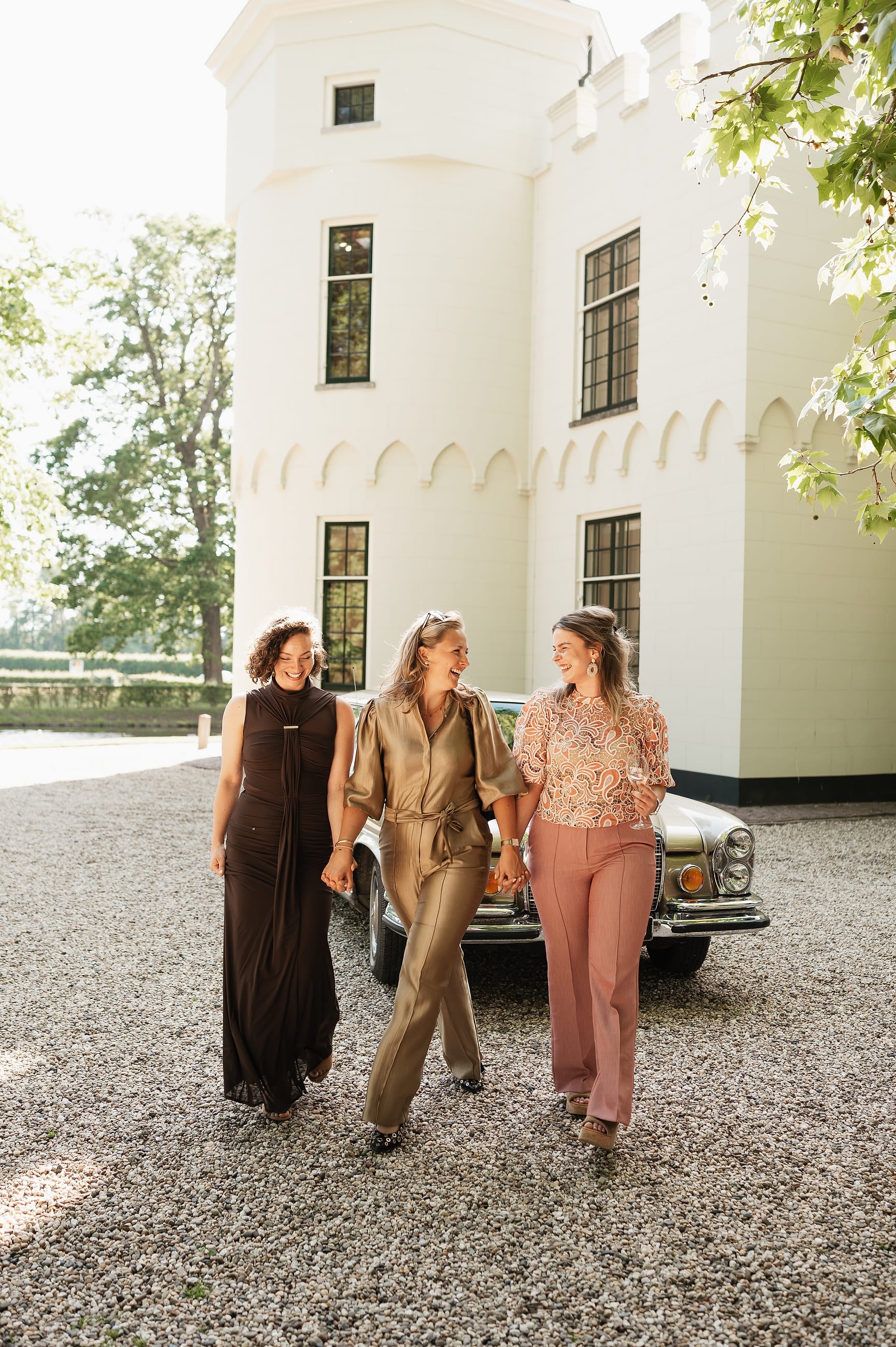 Bruid loopt met twee gasten langs het witte landhuis – Studio Roos Fotografie
