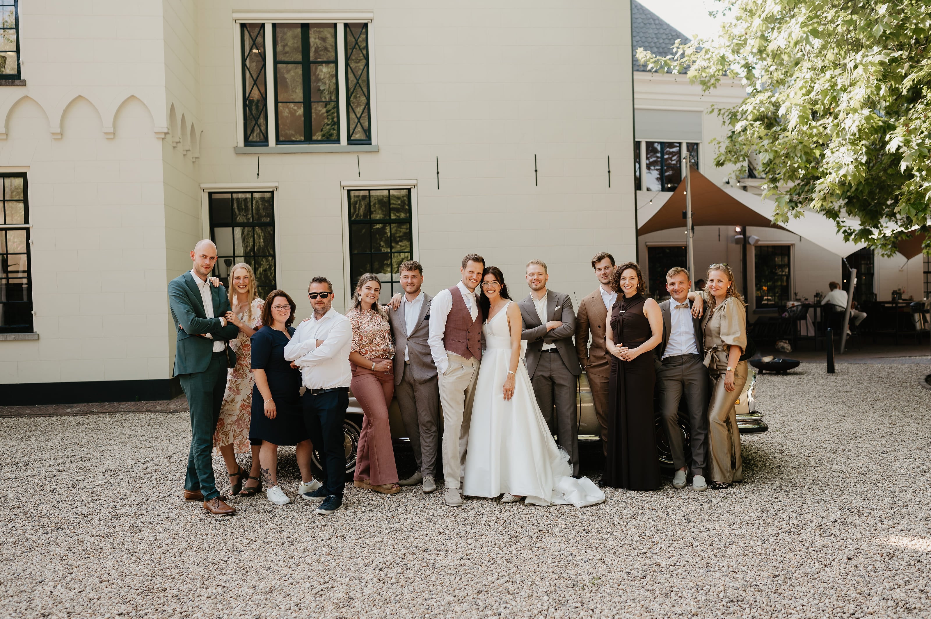 Groepsfoto van het bruiloftsgezelschap voor het landhuis – Studio Roos Fotografie