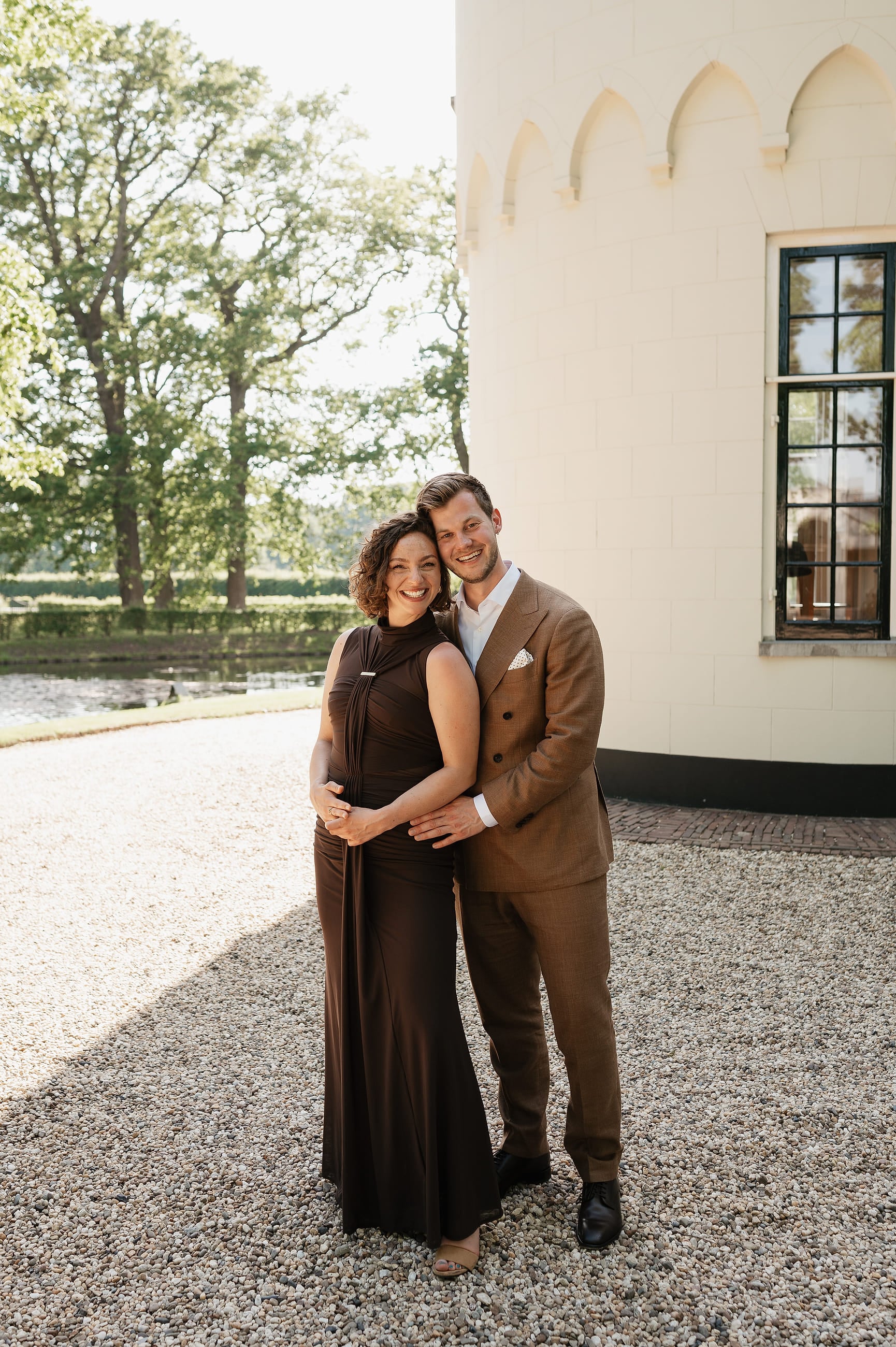 Bruidspaar omhelst elkaar bij de toren van het landhuis – Studio Roos Fotografie